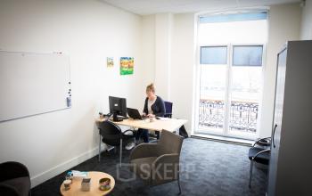 Interior view of a furnished office space rental at Kaldenkerkerweg 56, Venlo, with a person working at a desk.