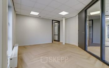 Modern office space in Venray at Keizersveld 47-47, featuring stylish wood flooring, ample lighting, and glass doors, ideal for office space rental. Suitable for creating a functional, bright working environment.