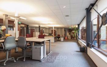 Spacious open floorplan office space rental at Kennedyplein 18, Venray, with modern furnishings, large windows, and bright lighting.