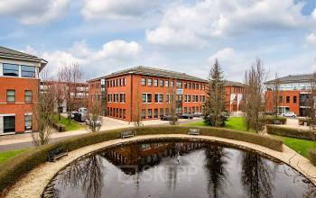 Exterior view of office building at Lange Dreef 10, Vianen Utr, showcasing a red-brick facade with multiple windows, and a small pond in the foreground, ideal for office space rental.