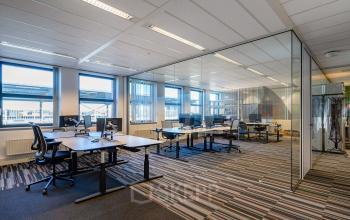 Open floorplan office space with modern glass partitions, multiple desks, and natural light, perfect for office space rental in Vianen Utr at Lange Dreef 10.