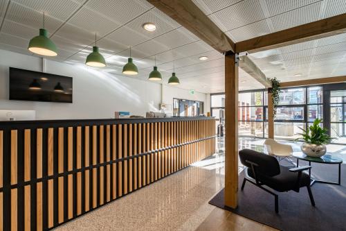 Modern reception area with sleek wooden counter and contemporary seating at office space rental location on Lange Dreef 10, Vianen Utr. Abundant natural light enhances the welcoming atmosphere.