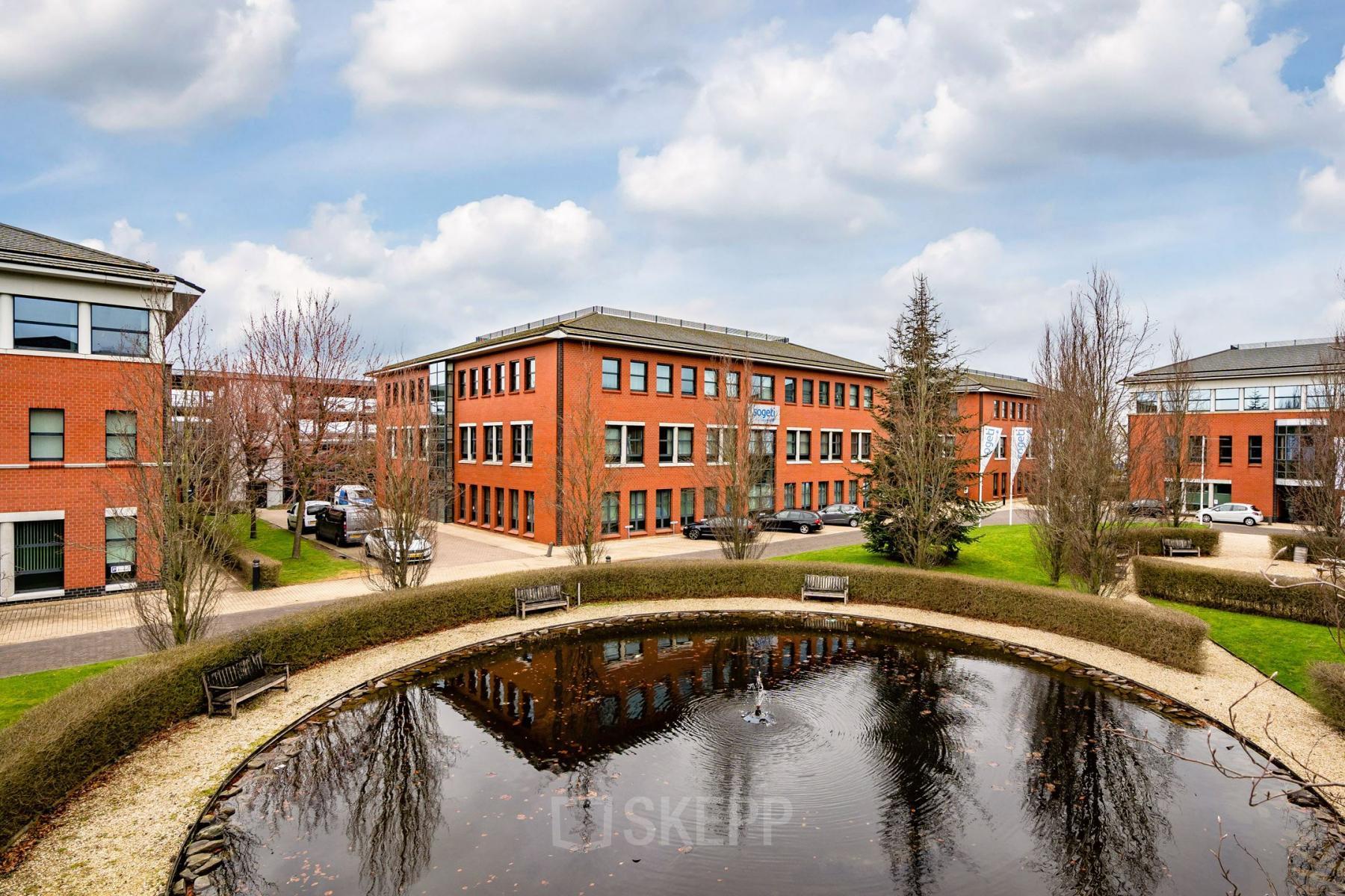 Exterior view of office building at Lange Dreef 10, Vianen Utr, showcasing a red-brick facade with multiple windows, and a small pond in the foreground, ideal for office space rental.