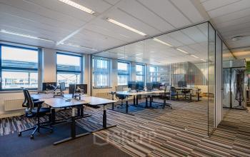 Modern office space at Lange Dreef 17, Vianen Utr, with glass partitions and colorful carpeting, available for office space rental. The workspace is bright and well-organized, featuring multiple desks and chairs.