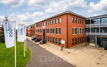 Exterior view of a modern office building at Lange Dreef 17, Vianen Utr, featuring red brick facade and adjacent parking area, ideal for office space rental.