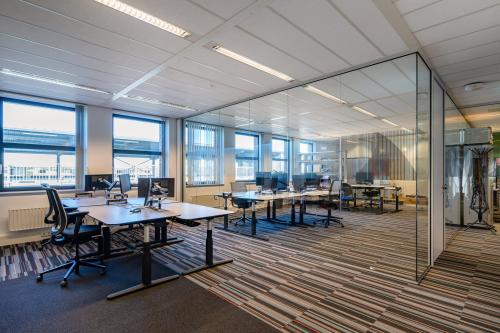 Modern office space at Lange Dreef 17, Vianen Utr, with glass partitions and colorful carpeting, available for office space rental. The workspace is bright and well-organized, featuring multiple desks and chairs.