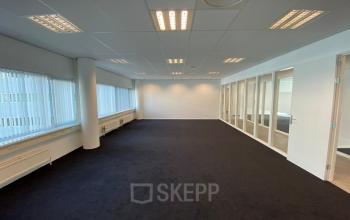 Spacious office to rent at Regulusweg 11, Voorburg, featuring large windows, neutral decor, and ample lighting, ideal for versatile workspace configurations.