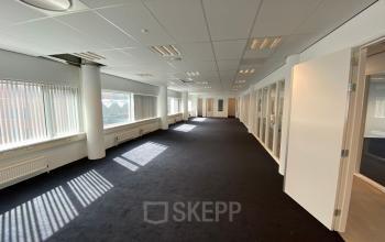 Spacious office interior at Regulusweg 11, Voorburg, featuring broad windows and neutral walls, perfect for an open-floor plan layout. Ideal for businesses seeking office space rental in a well-lit environment.