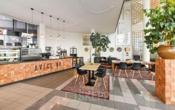 A furnished office space at Regulusweg 11, Voorburg, featuring a stylish coffee area with tables and chairs, ideal for office space rental.