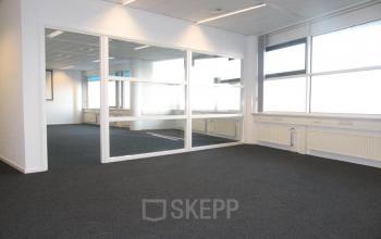 Bright, unfurnished office space available for rent at Regulusweg 11, Voorburg, featuring large windows and a glass partition for versatile office space rental options.