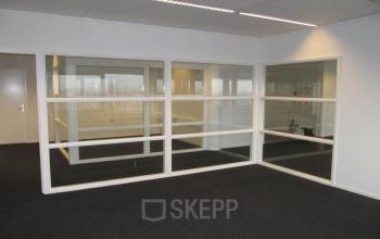 Interior view of office space at Regulusweg 11, Voorburg, featuring glass partitions and carpeted floors, ideal for those looking for office space rental.