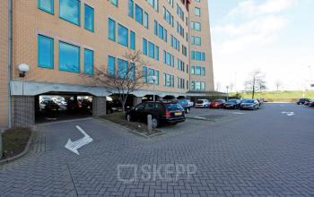Exterior view of office building, Loire 104 - 206 in Voorburg, showcasing parking area with multiple vehicles available for office space rental.