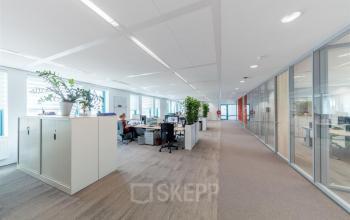 Bright Voorburg office space with desks and a worker engaged in business tasks, ideal for office space rental.