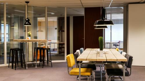 Interior view of an office space rental at Primulalaan 46-48, Waalre, featuring a large meeting table with chairs and contemporary lighting fixtures.