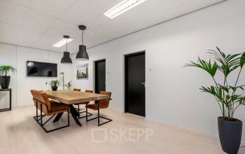 Bright office space at Agro Business Park 22, Wageningen, featuring a meeting table with chairs, plants, and modern lighting. Ideal for companies looking for office space rental.