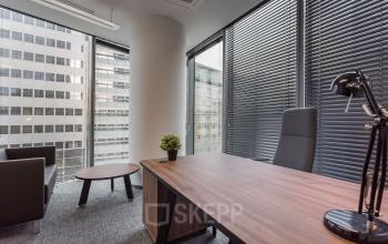 Eleganckie powierzchnie biurowe na wynajem przy Jana Pawła II 22 w Warszawa Śródmieście z drewnianym biurkiem, fotelami i dużymi oknami.