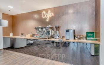 Nowoczesne i stylowe powierzchnie biurowe przy Jana Pawła II 22 w Warszawa Śródmieście, z przestrzenią kawiarnianą i neonowym napisem 'Café'.