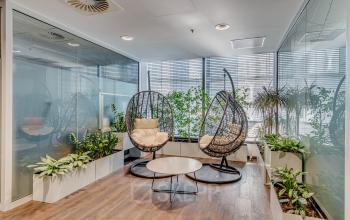 Stylowa przestrzeń biurowa na wynajem na Jana Pawła II 22 w Warszawie Śródmieście z eleganckimi fotelami i roślinami.