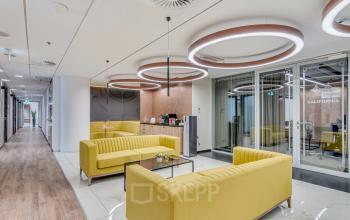 Elegancka strefa wspólna z wygodnymi żółtymi kanapami w nowoczesnym biurze na wynajem przy Jana Pawła II 22, w Warszawa Śródmieście.