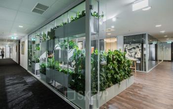 Nowoczesne powierzchnie biurowe w śródmieściu Warszawy przy Jana Pawła II 22, z zielenią i szklanymi przegrodami.