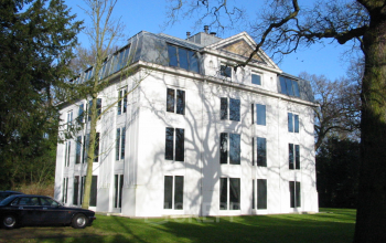 Exterior view of an office building located at Van der Oudermeulenlaan 1 in Wassenaar, featuring a white facade and large windows.
