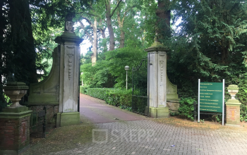 Entrance gate with stone pillars and lush greenery at Van der Oudermeulenlaan 1 in Wassenaar, a scenic location for office space rental.