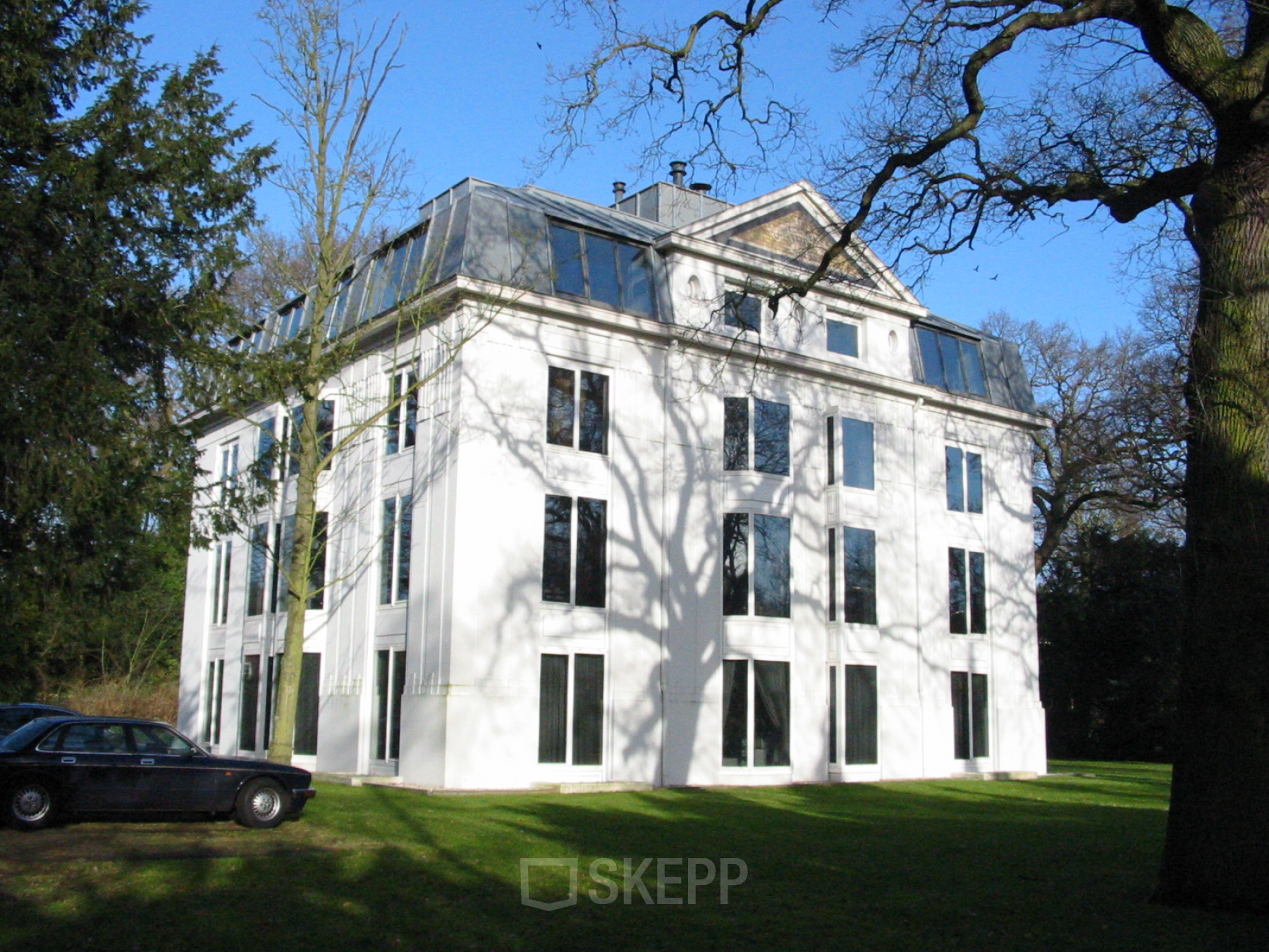 Exterior view of an office building located at Van der Oudermeulenlaan 1 in Wassenaar, featuring a white facade and large windows.