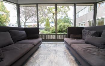 Elegant lounge area at Houttuinlaan 4 Woerden office to rent with comfortable sofas and a large window offering plenty of natural light.