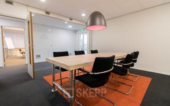 Modern conference room at Houttuinlaan 4 Woerden, with a large wooden table and comfortable chairs, ideal for an office space rental.