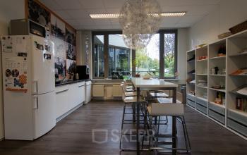 Modern office space rental at Houttuinlaan 4, Woerden, showing a well-lit pantry with shelves and a dining area.