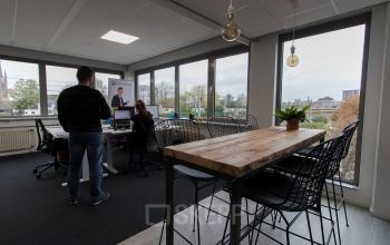 Modern office space rental at Houttuinlaan 4 in Woerden with employees engaged in business activities around a wooden table.