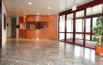 Reception area at Vijzelmolenlaan 20-26 in Woerden, featuring a modern wooden desk and a spacious, bright interior for office space rental.