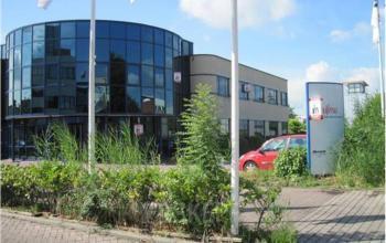 Modern exterior of a Woerden office space rental at Pelmolenlaan 5 with large windows and flagpoles.