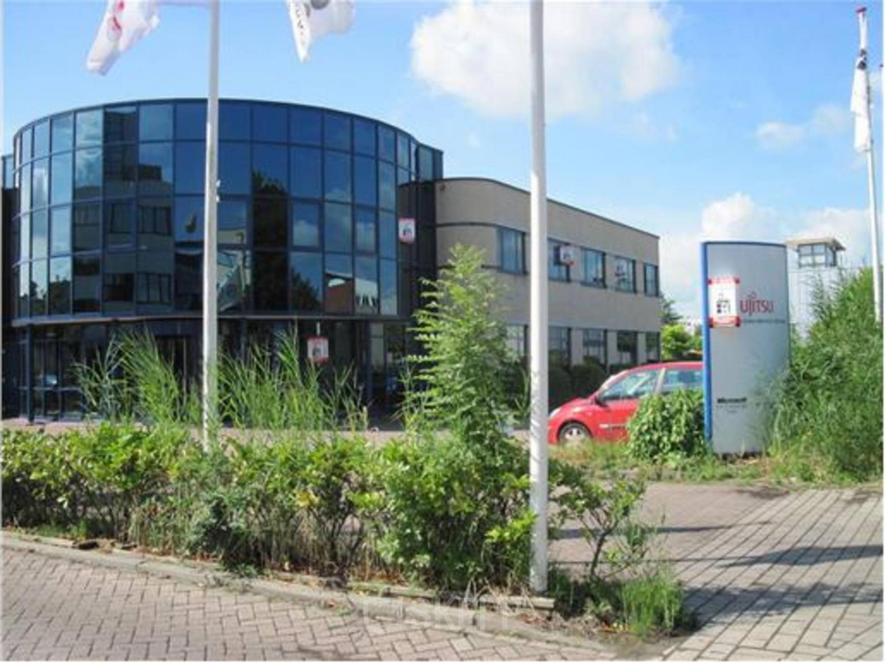 Modern exterior of a Woerden office space rental at Pelmolenlaan 5 with large windows and flagpoles.