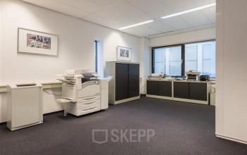 Office space for rent at Pelmolenlaan 17A in Woerden, featuring office equipment, cabinets, and large windows.