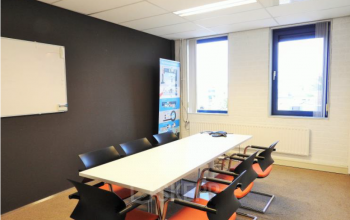 A professionally equipped office space rental at Pompmolenlaan 9, Woerden, with a conference table, chairs, and a whiteboard.
