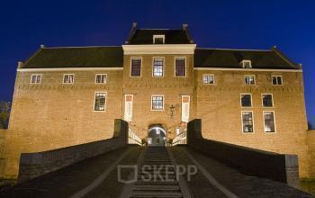 Night view of the office building facade at Wipmolenlaan 3, offering office space rental in Woerden with illuminated windows and a grand entrance staircase.