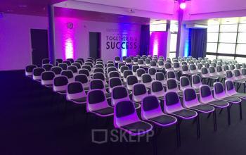 Modern conference room at Korenmolenlaan 4 in Woerden, equipped for presentations with rows of chairs and ambient lighting ideal for those looking to rent office space.