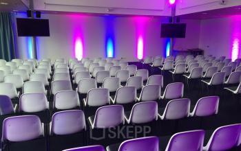 Modern conference room at Korenmolenlaan 4, Woerden, with colorful lighting and chairs arranged for a presentation, ideal for office space rental.