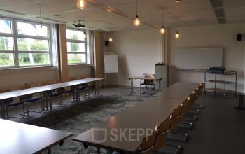 Spacious Woerden office space rental at Korenmolenlaan 4 with long tables, chairs, and bright windows.