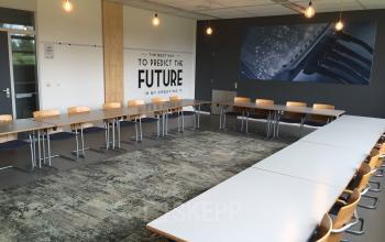 Well-appointed conference room available for office space rental at Korenmolenlaan 4, Woerden, featuring a large meeting table and inspiring wall art.
