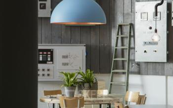 Modern office space rental at Korenmolenlaan 4, Woerden, featuring a stylish pendant lamp, wooden tables, and designer chairs in a well-lit area.