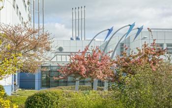 Modern office space rental at Korenmolenlaan 4, Woerden, with artistic architectural details and blossoming trees in the foreground.