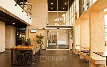 Elegantly designed office space rental at Trasmolenlaan 5, Woerden, featuring a wooden communal table and modern lighting.