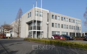 Exterior view of the office building at Pompmolenlaan 18, Woerden, with parking area in front. Ideal office space rental location.
