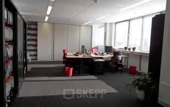 Office space for rent at Pompmolenlaan 18 in Woerden with desks, chairs, and shelves, natural light from large windows.