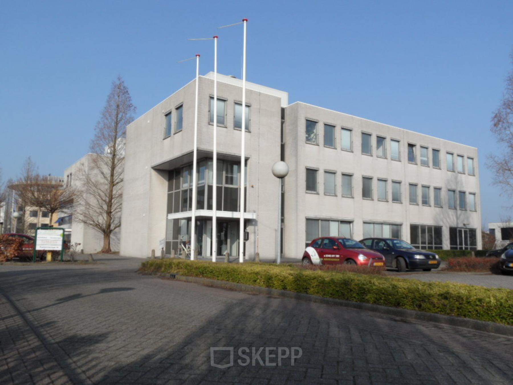 Exterior view of the office building at Pompmolenlaan 18, Woerden, with parking area in front. Ideal office space rental location.