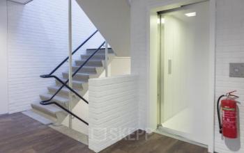 Unfurnished office interior at Pompmolenlaan 9 features an elevator and staircase, ideal for office space rental.