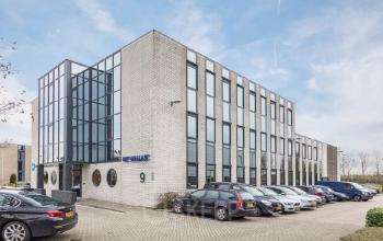 Exterior view of a modern office building at Pompmolenlaan 9, Woerden, offering office space rental with ample parking.