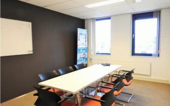 Bright office space at Pompmolenlaan 9, Woerden, featuring a meeting table and chairs near large windows, ideal for office space rental.